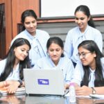 A group of young South Asian women working together on a laptop in a Jaipur office.