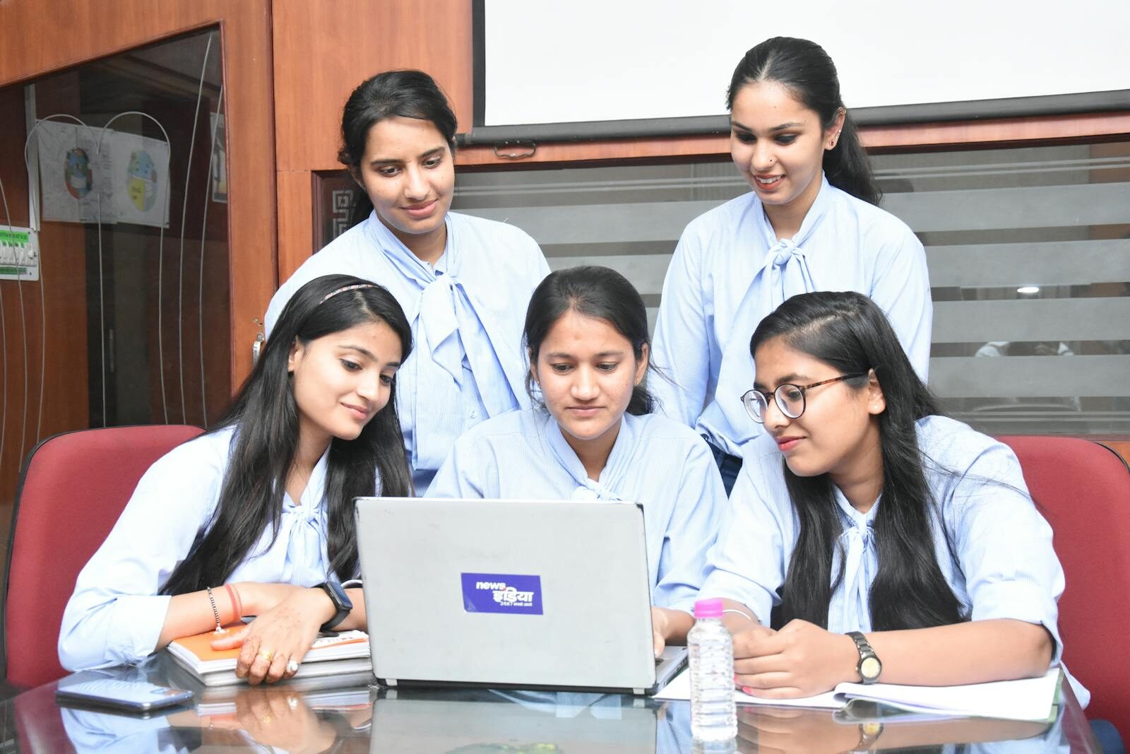A group of young South Asian women working together on a laptop in a Jaipur office.