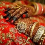 Close-up of ornate henna designs and traditional jewelry on a bride's hands, highlighting Indian wedding elegance.
