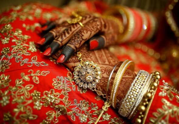 Close-up of ornate henna designs and traditional jewelry on a bride's hands, highlighting Indian wedding elegance.