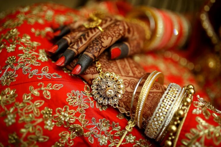 Close-up of ornate henna designs and traditional jewelry on a bride's hands, highlighting Indian wedding elegance.