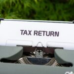 a close up of a typewriter with a tax return sign on it