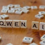 A wooden table topped with scrabble tiles spelling queen ali
