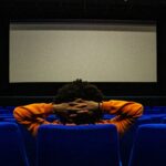 a person sitting in a chair in front of a projection screen